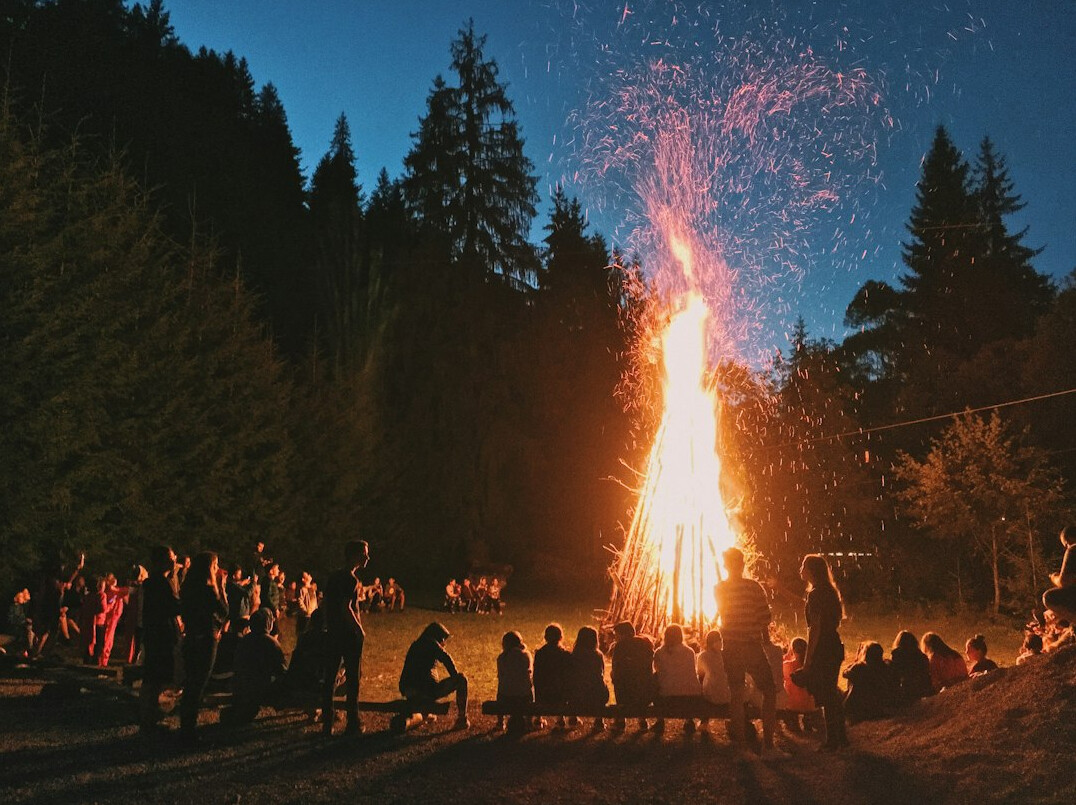 Crowd gathered around a bonfire celebration at dusk